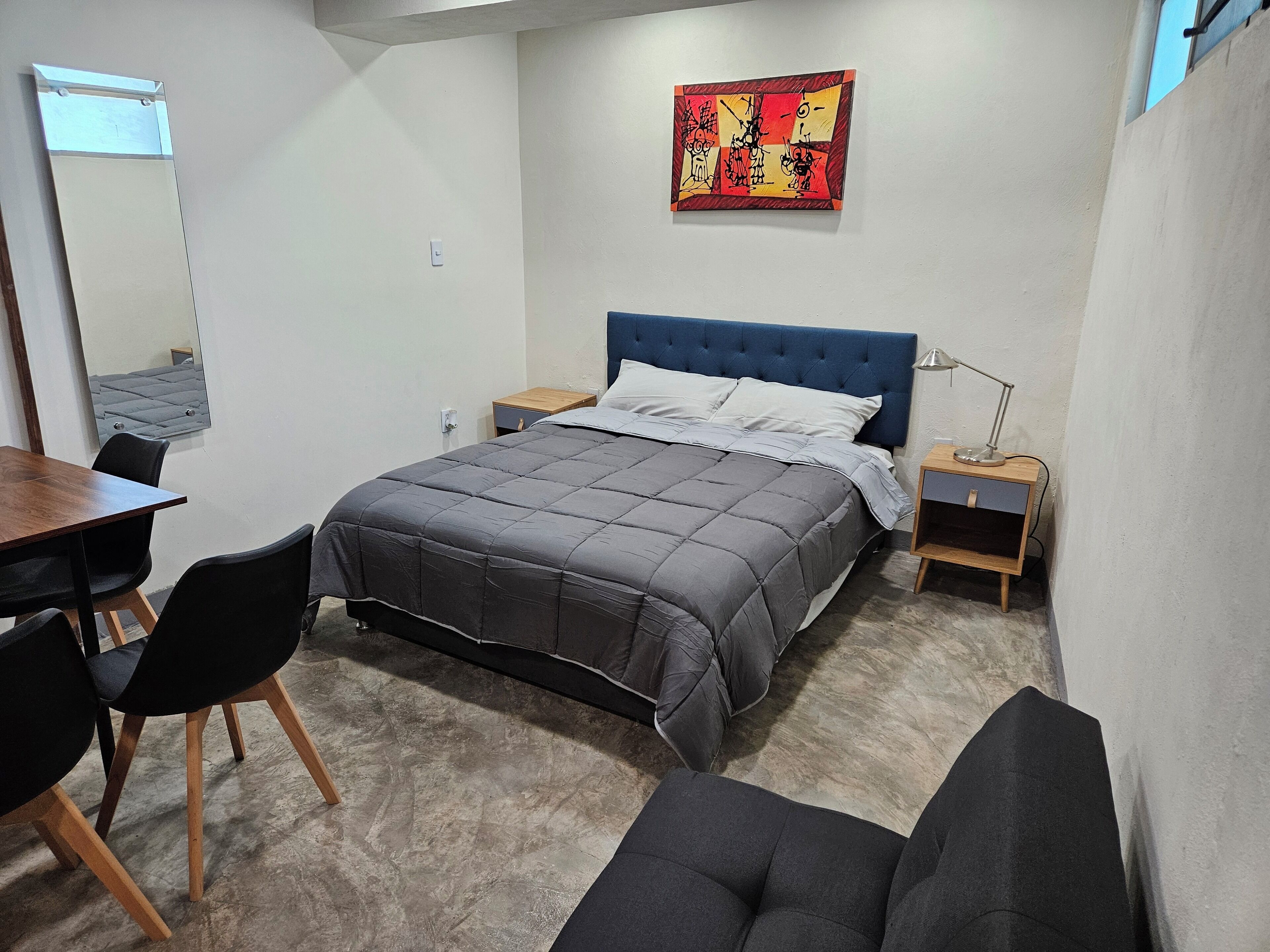 A bedroom with a bed, bedside tables, a desk, and chairs.