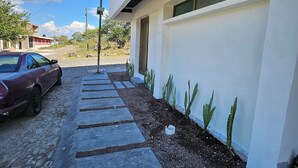 Un edificio moderno con entrada pavimentada y un automóvil estacionado.