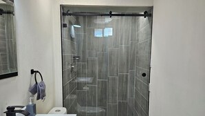 Un baño moderno con ducha vidriada, lavamanos blanco y retrete.