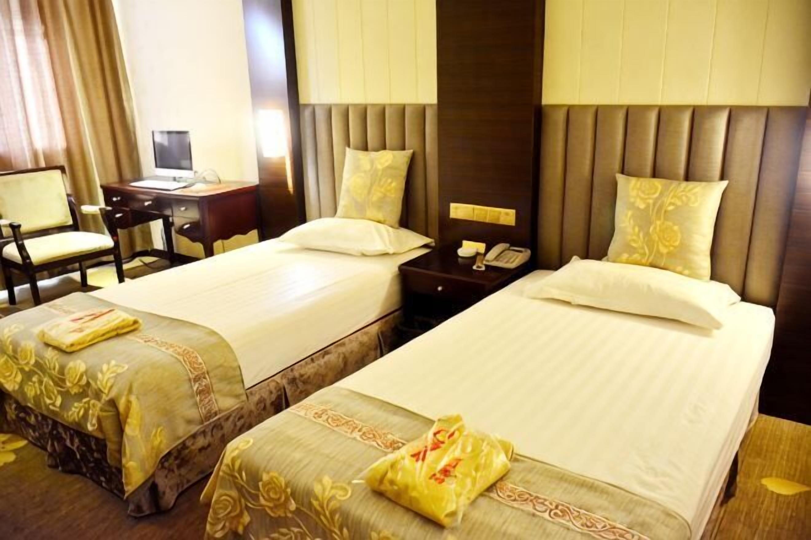 A hotel room with two beds, a desk, a chair, and a telephone.