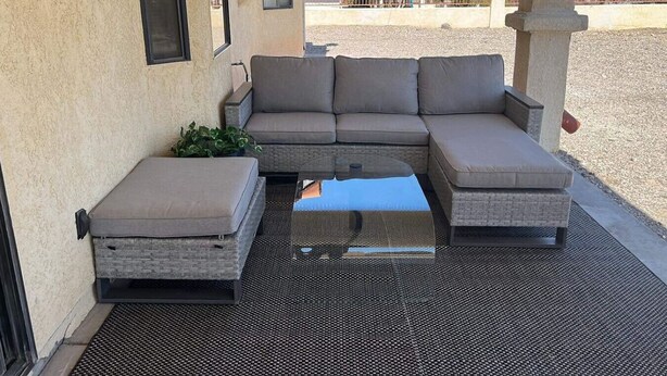 An outdoor seating area with a sectional sofa and a small table, set against a building with a textured wall and a metal roof. - Best Pet Friendly Home In Bullhead City (Bullhead City)