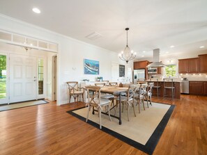 A spacious kitchen with wooden cabinets, a large island, and a dining area with chairs. - Lake Gaston Main Lake Home, expansive view  and water toys! (Boydton)