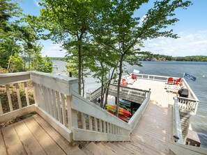 A wooden deck with a railing, a dock extending into a lake, and a flag with "Pennsylvania" on it. - Lake Gaston Main Lake Home, expansive view  and water toys! (Boydton)