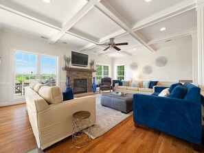 A spacious living room with a fireplace, comfortable seating, and large windows offering a view of the outdoors. - Lake Gaston Main Lake Home, expansive view  and water toys! (Boydton)
