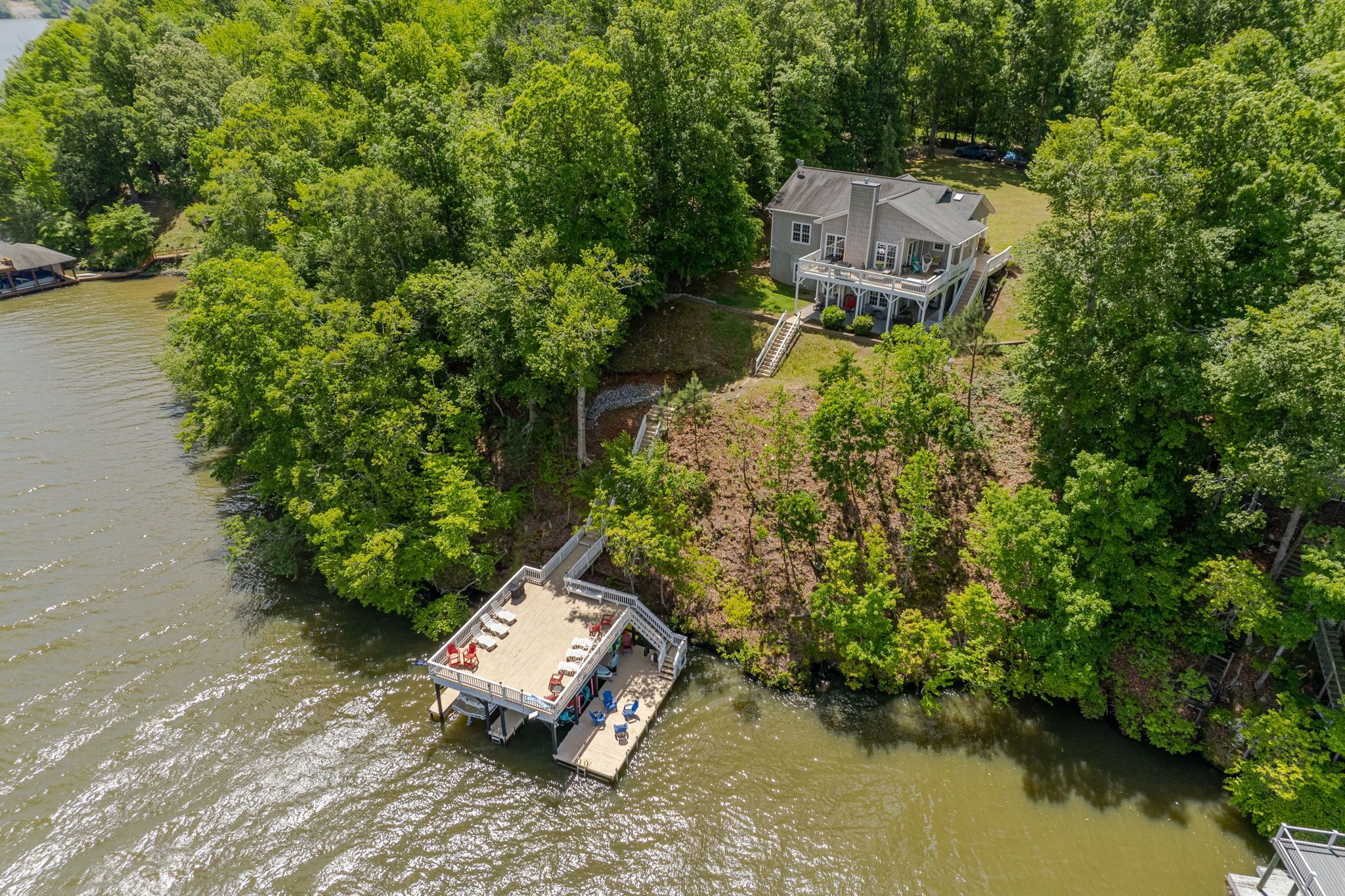 An aerial view of a lakeside property with a dock, a house, and a boat.