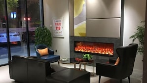 A modern living room with a fireplace, black leather sofas, and a view of the street through large windows. - Home Inn (Sheyang Renmin Road) (Sheyang)
