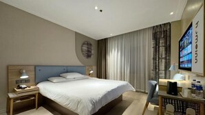 A modern hotel room with a large bed, a desk with a chair, a TV, and a wall-mounted screen displaying content. - Home Inn (Sheyang Renmin Road) (Sheyang)