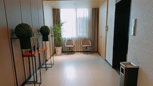 A hallway with a potted plant, two chairs, and a trash bin. - Home Inn (Sheyang Renmin Road) (Sheyang)