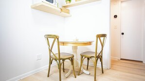 A dining area with a round table and two chairs, a microwave on a shelf, and a door in the background. - Somerset- Luxury Condominium in Birmingham (Birmingham)