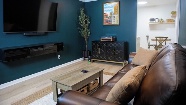 A living room with a flat-screen TV, a coffee table, a leather sofa, a cabinet, and a painting on the wall. - Somerset- Luxury Condominium in Birmingham (Birmingham)