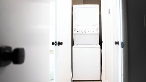 A compact, white laundry room with a built-in washer and dryer, featuring a simple, functional design and a small window. - Somerset- Luxury Condominium in Birmingham (Birmingham)