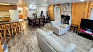 Una sala de estar acogedora con chimenea, un comedor con muebles de madera y una cocina con armarios de madera.