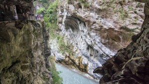 A narrow canyon with a river running through it, a bridge, and a railing for safety. - Ocean Hotel (Hualien)