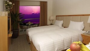 A hotel room with a bed, a desk, a chair, and a view of the sunset. - Ocean Hotel (Hualien)