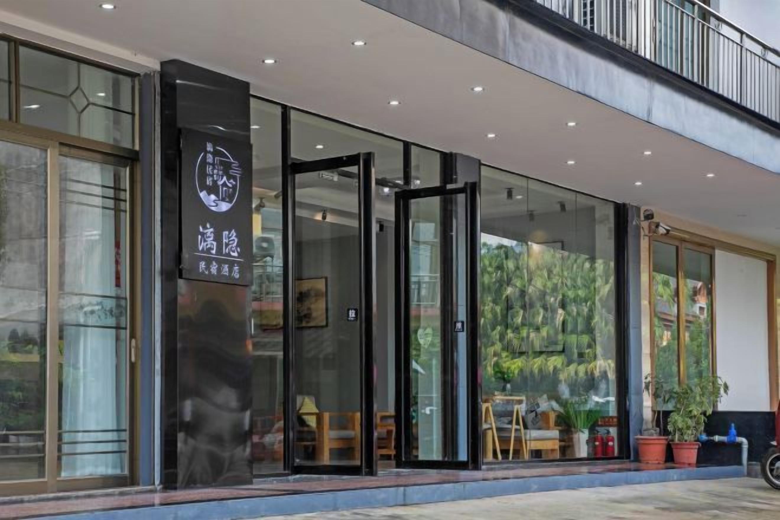 A modern building with a glass entrance, a sign with Chinese characters, and outdoor seating.