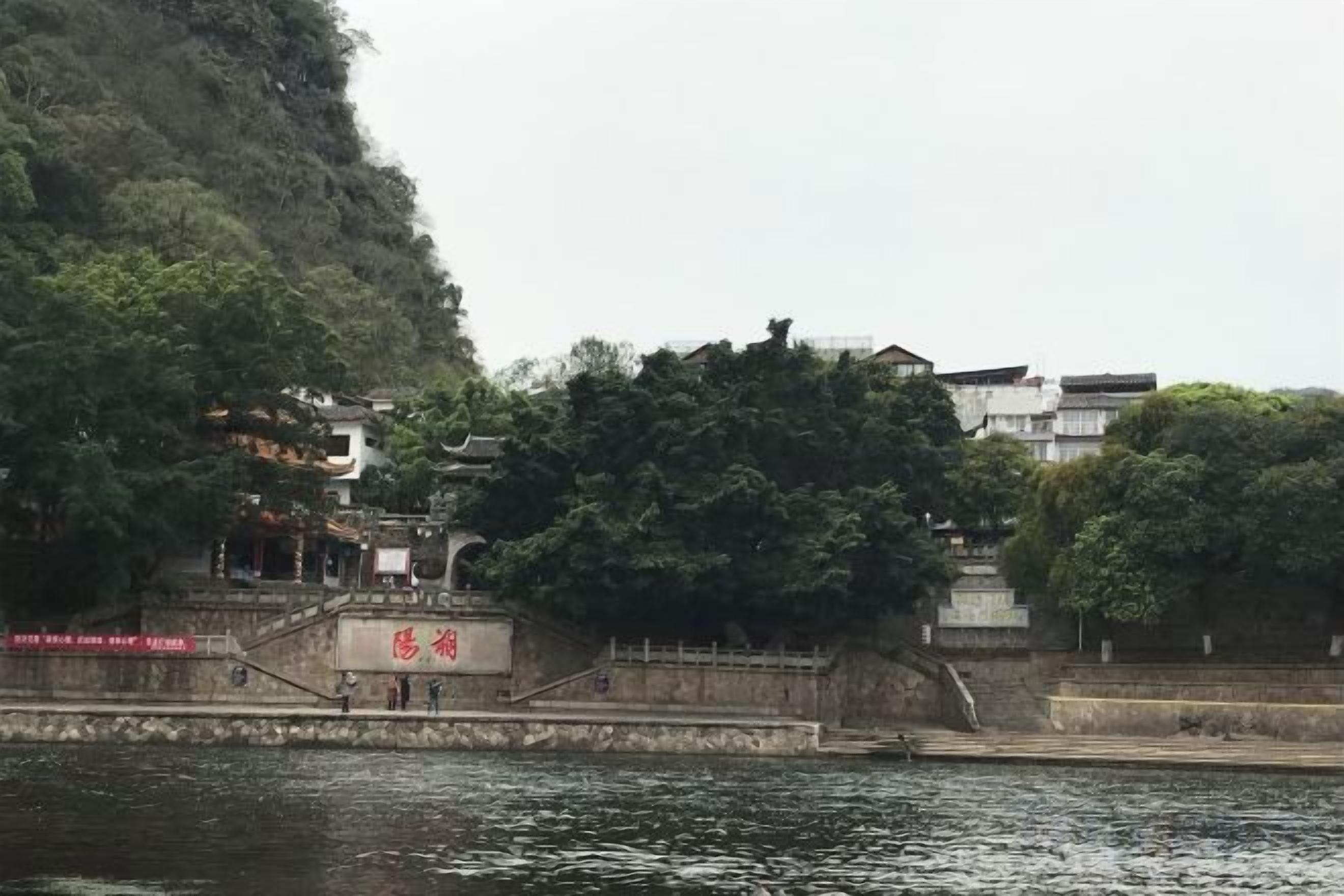 A riverside view with a bridge, buildings, and greenery.