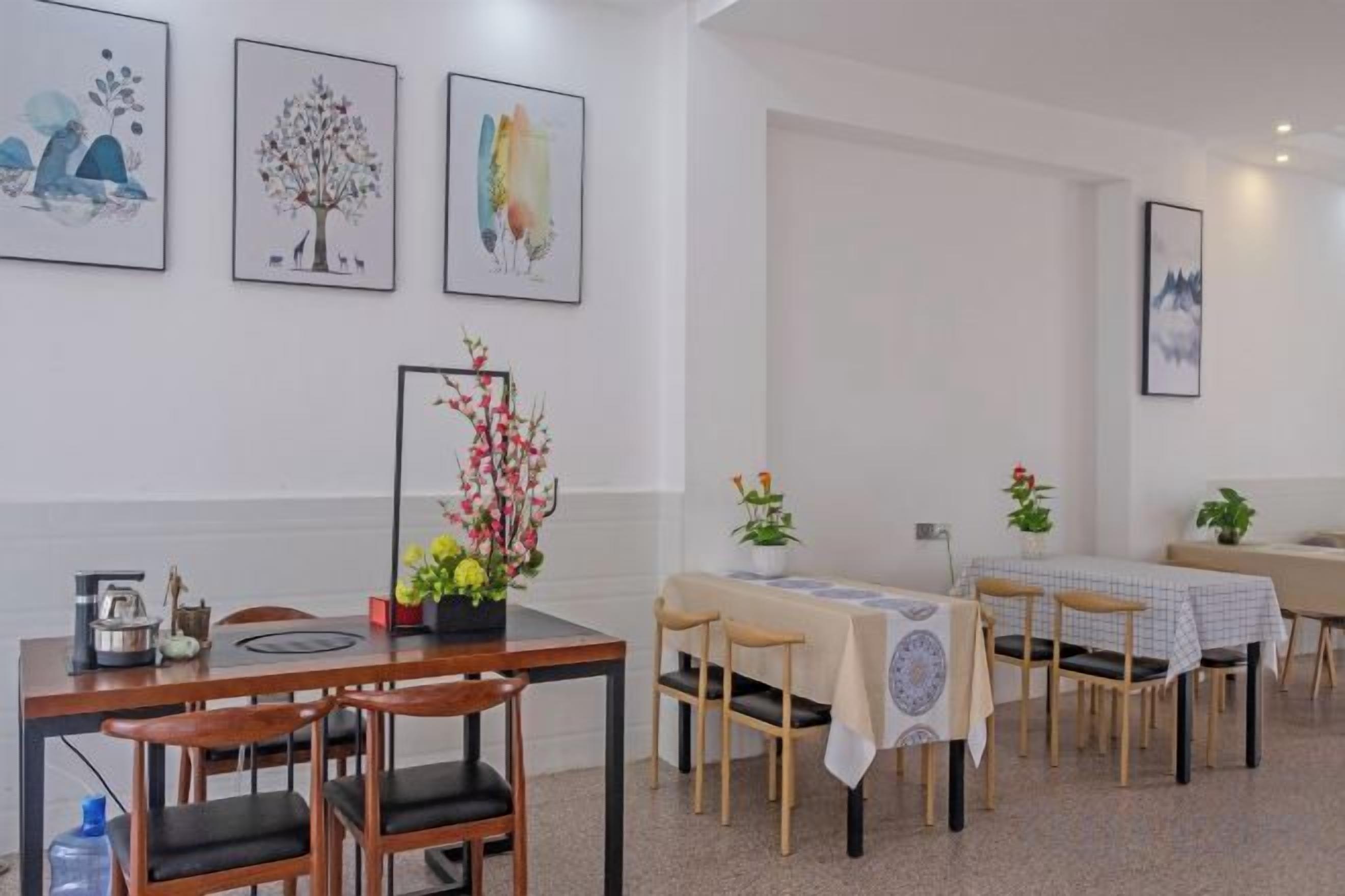 Un coin repas avec une table dressée pour quatre personnes, des chaises et un vase de fleurs.