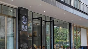 En moderne bygning med en glasfacade, et skilt med kinesiske tegn, og en dør der fører ind.