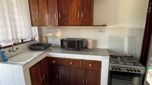 Una cocina con armarios de madera, microondas, estufa a gas y un lavamanos.