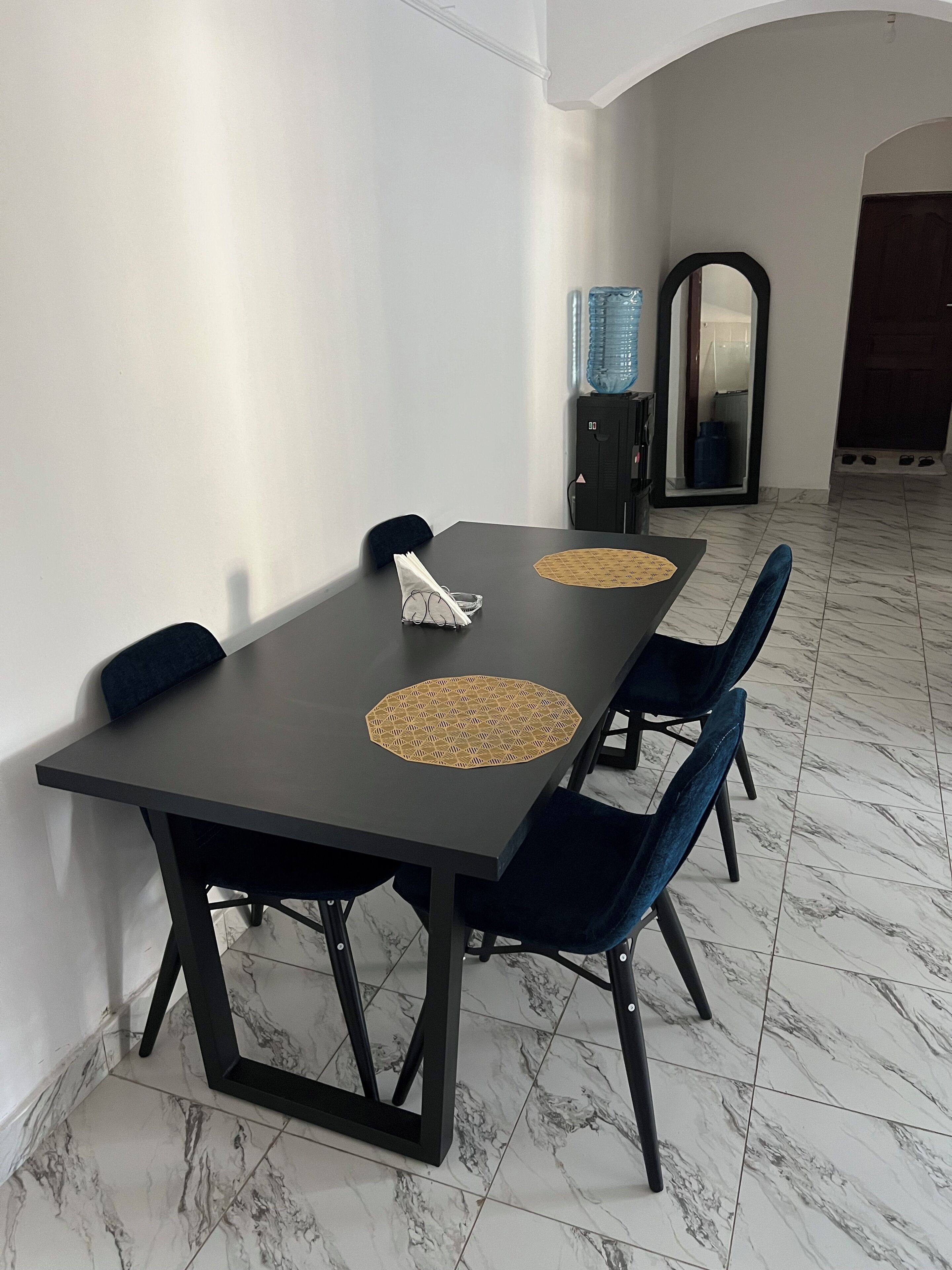 Een eethoek met een rechthoekige tafel, donkere stoelen en een tafelmat met een patroon.