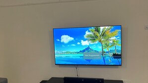 Un televisor de pantalla plana montado en la pared con un mueble de madera debajo.