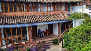Um edifício tradicional com telhado ladrilhado, janelas de madeira e um alpendre coberto.