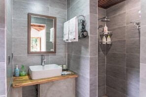 A bathroom with a rectangular sink, a mirror, and a shower area.