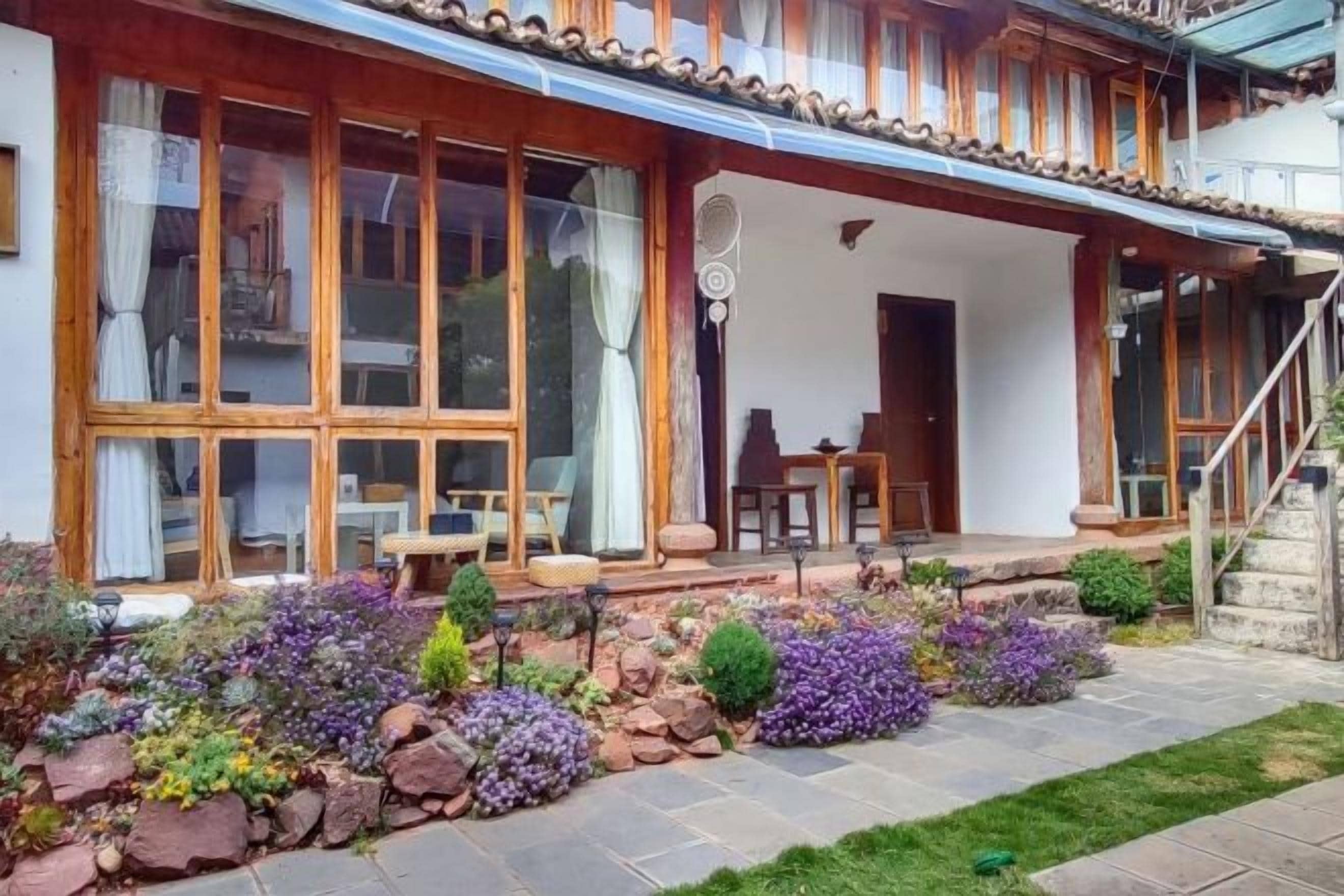 A traditional house with a covered porch, stone pathway, and a small garden with various plants.