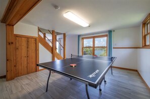 Enjoy a game of ping pong in this spacious room, featuring a staircase and large window.