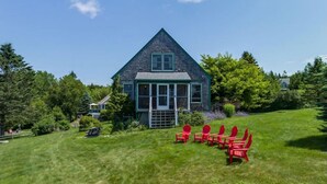 A house with a green porch and red chairs. - Charming 3-bedroom waterfront cottage in Tremont with spectacular sunsets. (Tremont)