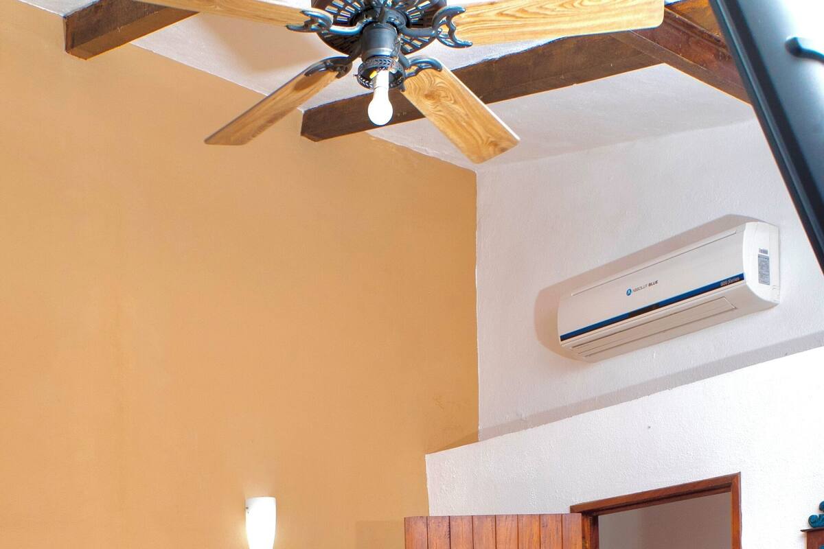 Une chambre avec un lit en bois, un ventilateur de plafond et un appareil de climatisation.