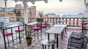 Una terraza con mobiliario exterior, una planta en maceta y vista al mar.