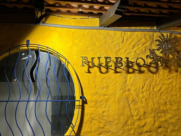 Pared amarilla con el texto "FUEBLO PUERTO" y una reja de metal.