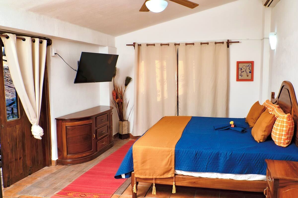 Une chambre à coucher avec un lit, des meubles en bois, une télévision et une moquette rouge.