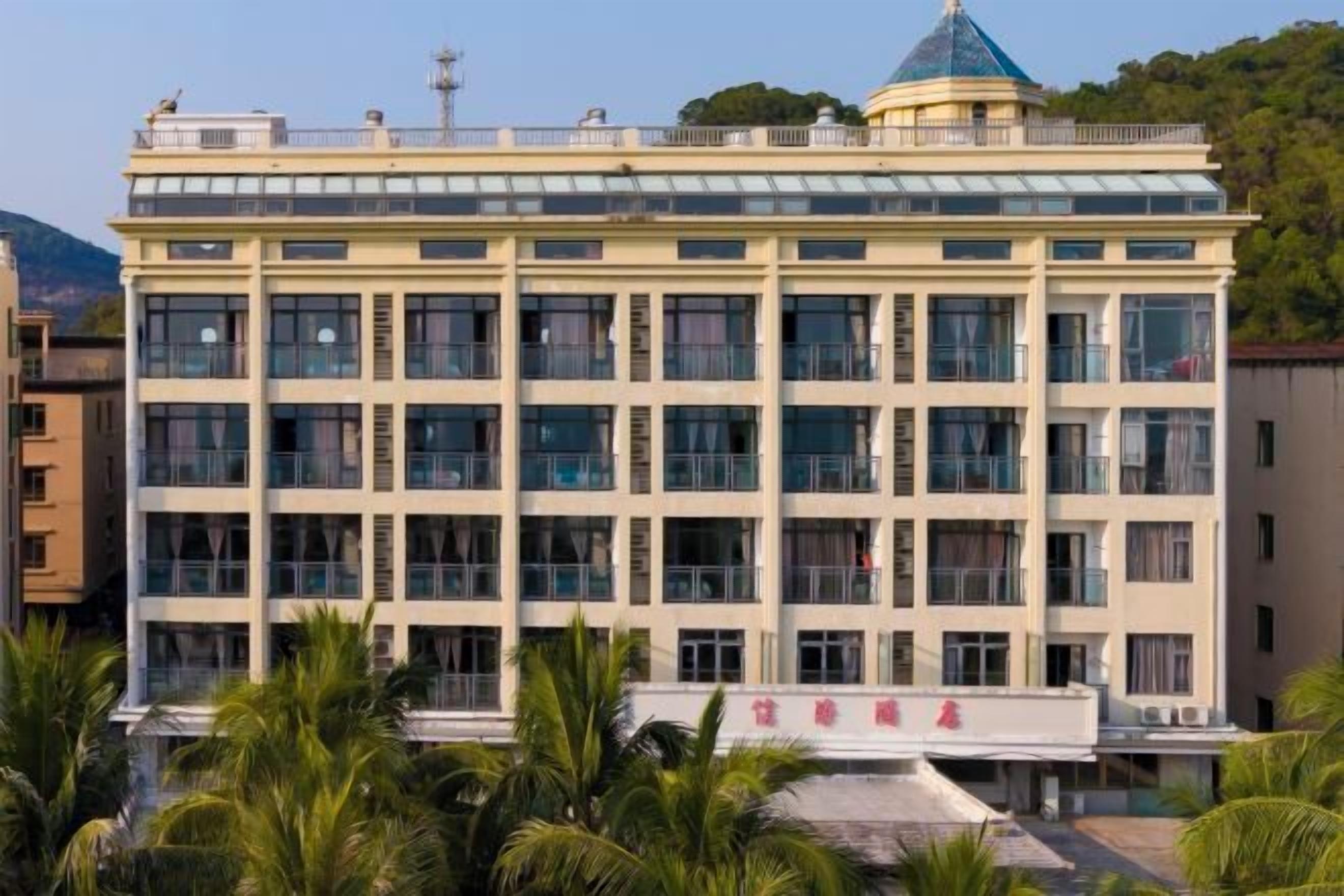 Un immeuble à étages doté d’une façade symétrique, de grandes fenêtres et d’un dôme vert distinctif sur le toit.