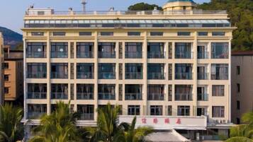 Un immeuble à étages doté d’une façade symétrique, de grandes fenêtres et d’un dôme vert distinctif sur le toit.