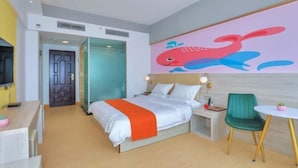 Een hotelkamer met een bed, nachtkastje, stoel en een muur met een walvismuurdecoratie.