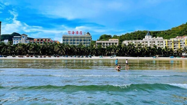 Een strandhotel met een zwembad, zitplaatsen aan het strand en uitzicht op de oceaan.