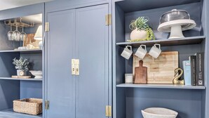 Ein Zimmer mit einem grauen Schrank, Regalen mit Dekorationen, einem Holzschneidebrett und einer Schüssel.
