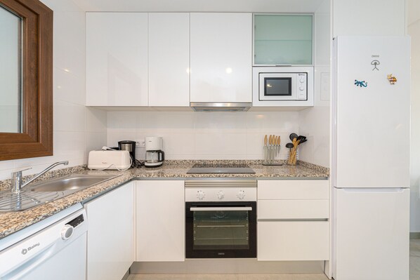 A modern kitchen with white cabinets, a built-in oven, a microwave, and a dishwasher. - Apartamento Narcisos (Mar de Pupi) (San Juan de los terreros)