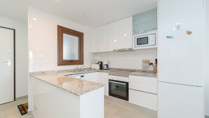 Eine moderne Küche mit weißen Schränken, einer Granit Arbeitsplatte, einer eingebauten Mikrowelle und einem Kühlschrank.