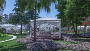 A garden with a white gazebo, surrounded by lush greenery and purple flowers. - Sun City Huiyue Hotel (Daying)