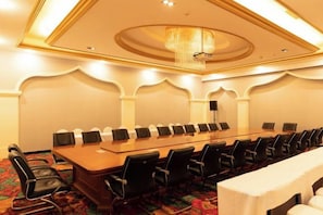 Un salón de conferencias con una mesa larga, sillas y un candelabro.