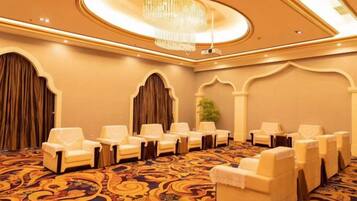 A conference room with a patterned carpet, rows of chairs, and a chandelier.