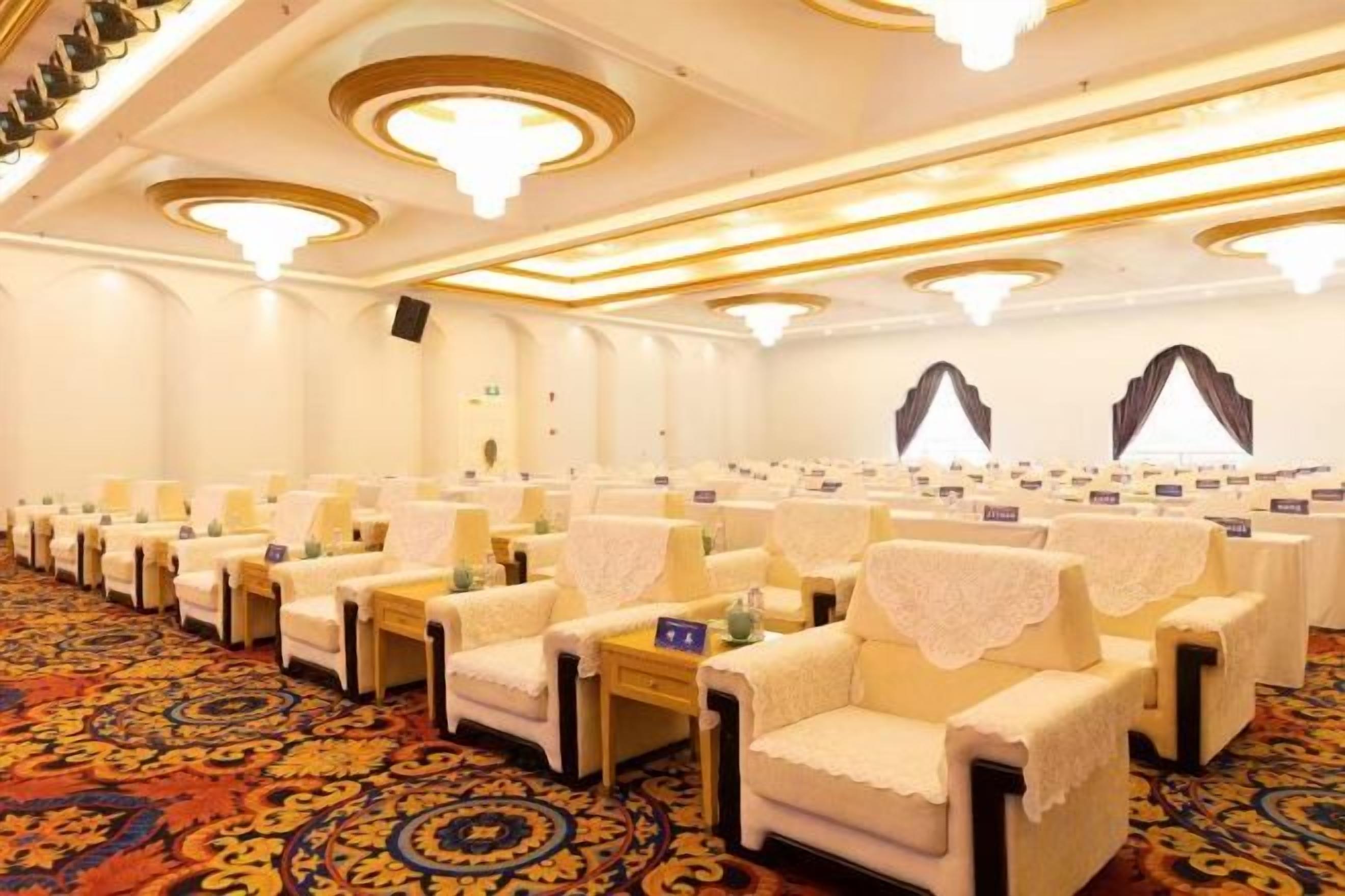 A conference room with rows of chairs, tables, and a carpeted floor.