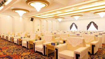 A conference room with rows of chairs, tables, and a carpeted floor.