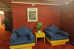 A room with two blue sofas, a small table with a plant, and a framed picture on the wall. - Sun City Huiyue Hotel (Daying)