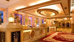 A lobby with a marble reception desk, a red carpet, and a chandelier. - Sun City Huiyue Hotel (Daying)