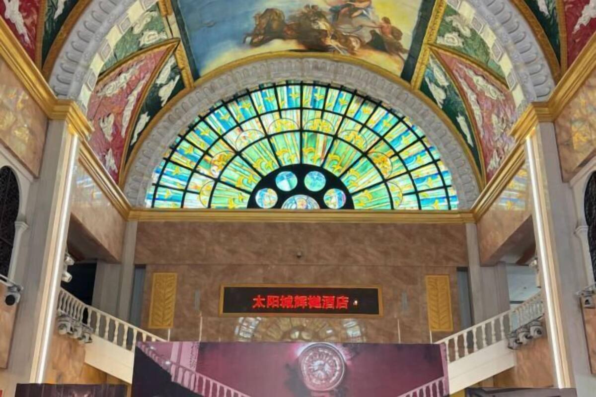 A grand arched stained glass window with a circular design, a sign indicating a hotel, and classical architectural details.
