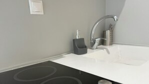 A modern kitchen with a black induction cooktop, a white countertop, and a stainless steel faucet. - DOM SUITES (Daratsos)